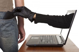Internet theft - a gloved hand reaching through a laptop screen 