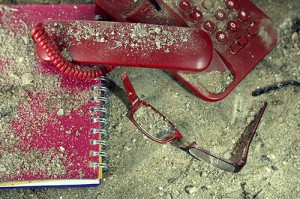 Broken phone, notebook and glasses, in the dirt and covered in dust