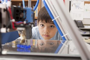 Boy intently watches 3D printer