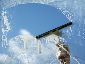 Photo of pulling a squeegee across a soapy window on a sunny day.