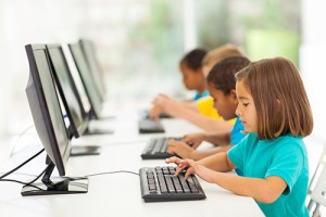 Photo of 4 elementary school children typing at desktop computers.