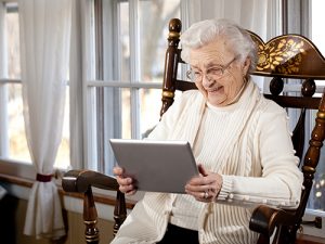 Photograph of smiling elderly woman using a tablet computer.
