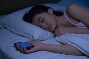 A woman sleeps clutching a smart phone.